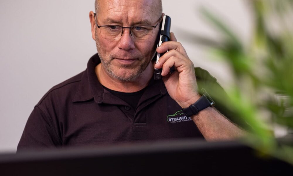 image of Straight-N-Paint employee on the phone to collision repair customer in Rangiora-based car repair shop