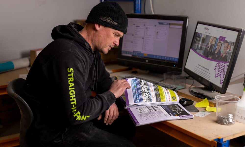 image of Straight-N-Paint mechanic reviewing auto parts catalogue in Rangiora, North Canterbury