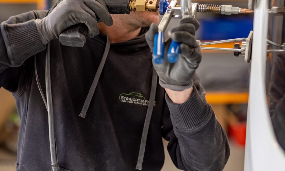 Straight-N-Paint auto repairer performing panel beating on a car in the Rangiora workshop