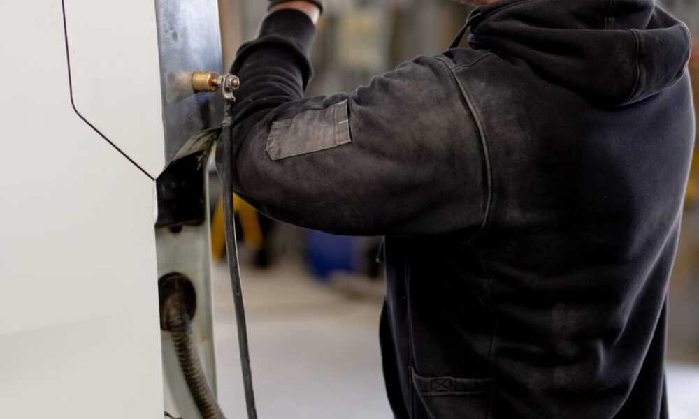 Straight-N-Paint auto repairer performing vehicle dent removal on a car in the Rangiora workshop