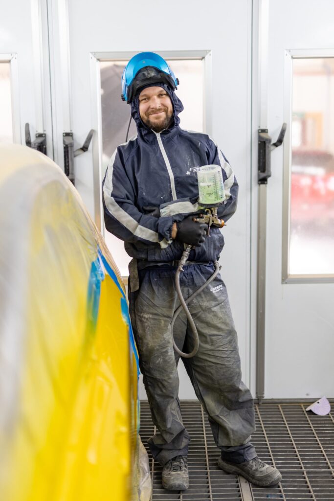 image of Straight-N-Paint employee wearing spray painting PPE and holding spray painting equipment in Rangiora auto workshop