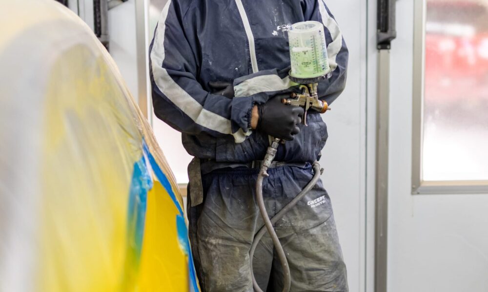 image of Straight-N-Paint employee wearing spray painting PPE and holding spray painting equipment in Rangiora auto workshop