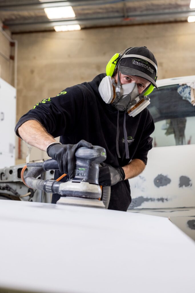 Straight-N-Paint automotive repairer performing panel beating on a vehicle in the Rangiora workshop, Canterbury