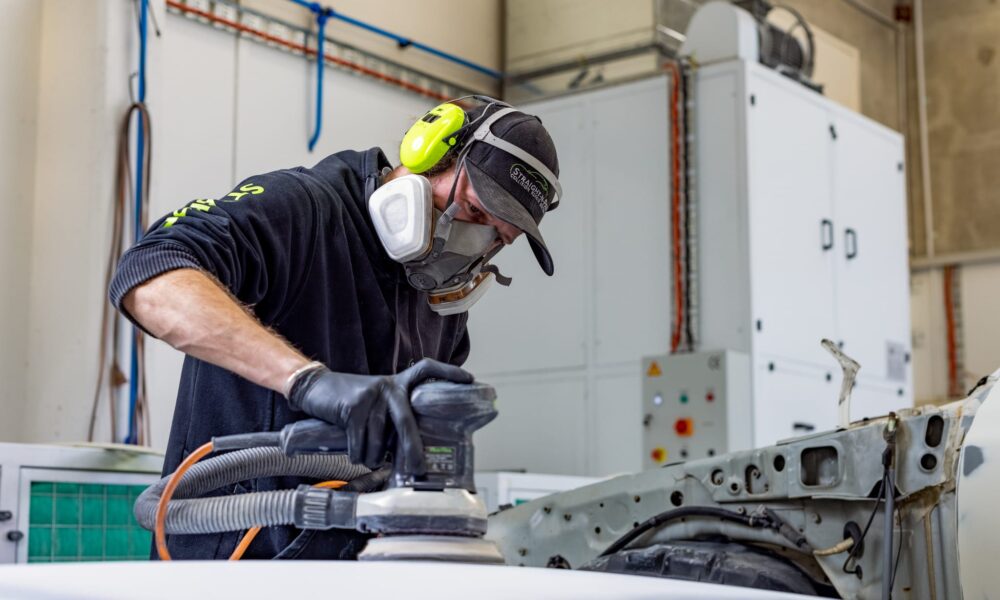 Straight-N-Paint auto repairer performing panel beating on a car in the Rangiora workshop