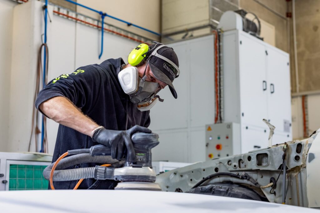 Straight-N-Paint auto repairer performing panel beating on a car in the Rangiora workshop